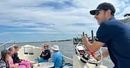 Captain steering charter boat with guests on sunny coastal waters