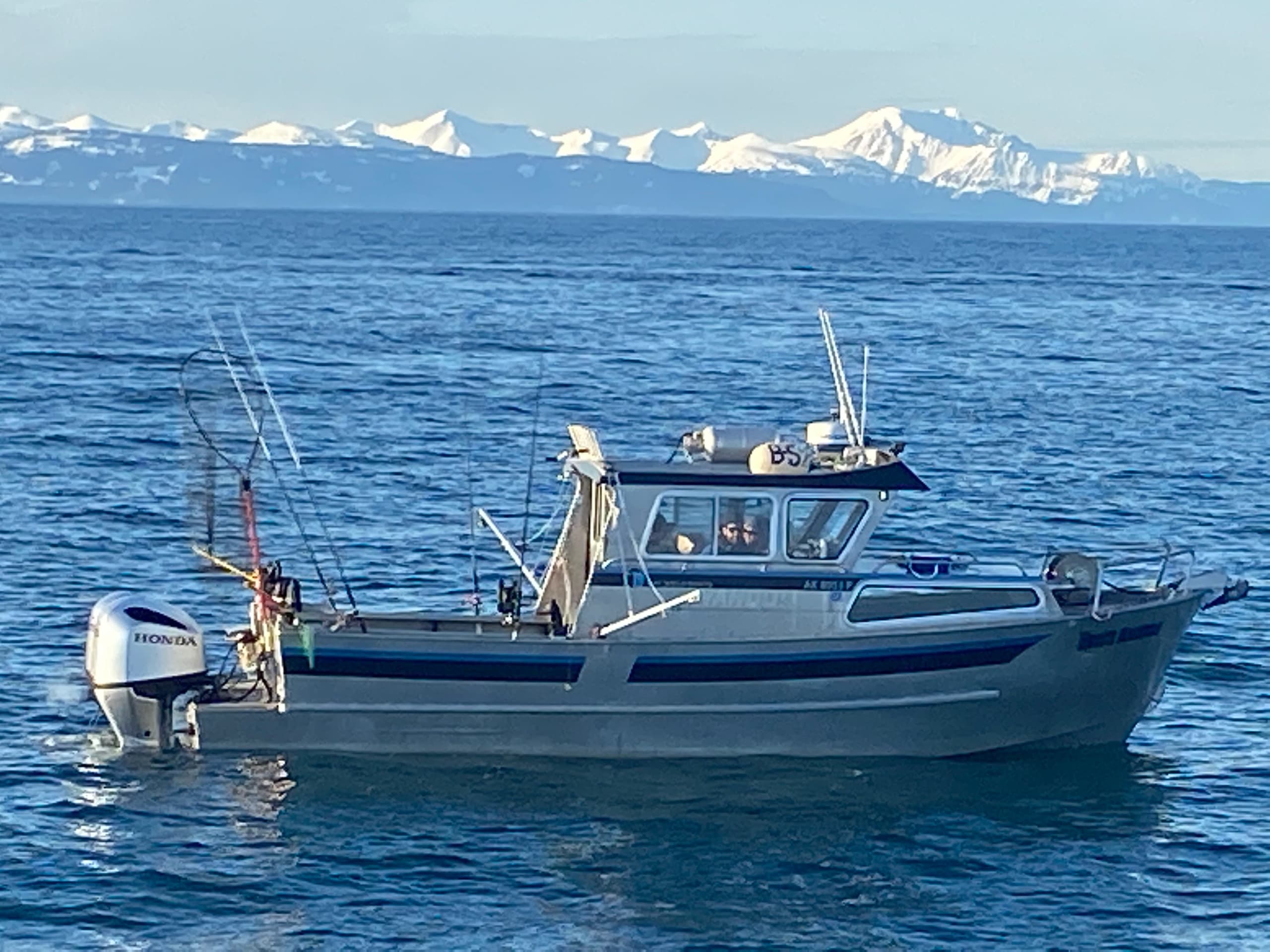 Vertical shot of small fishing boat with snowy mountain backdrop