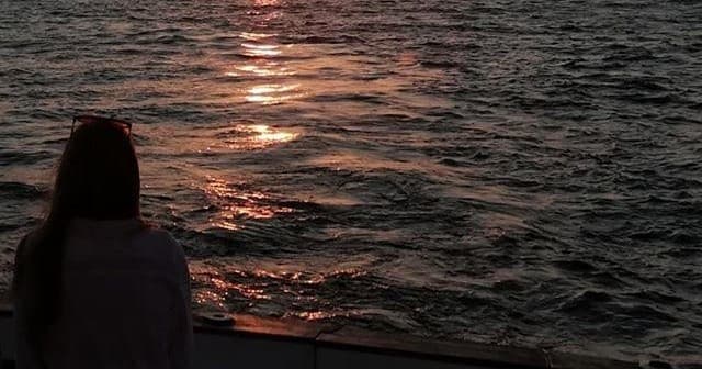 Person watching ocean sunset from boat, peaceful evening view