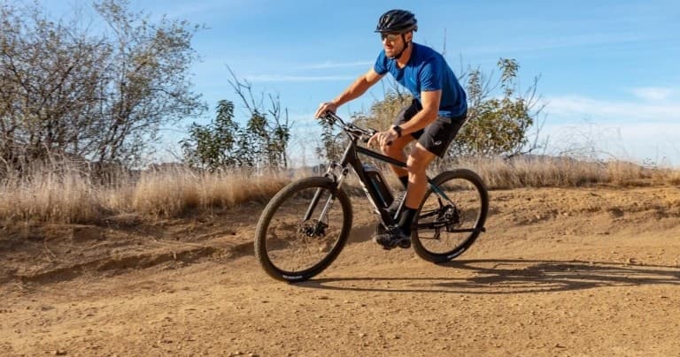 Mountain biker riding scenic dirt trail in pine forest