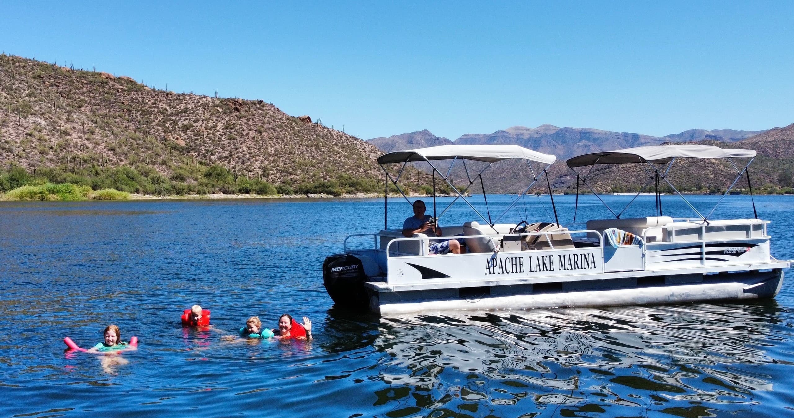 Tour boat and swimmers enjoying Apache Lake near shore
