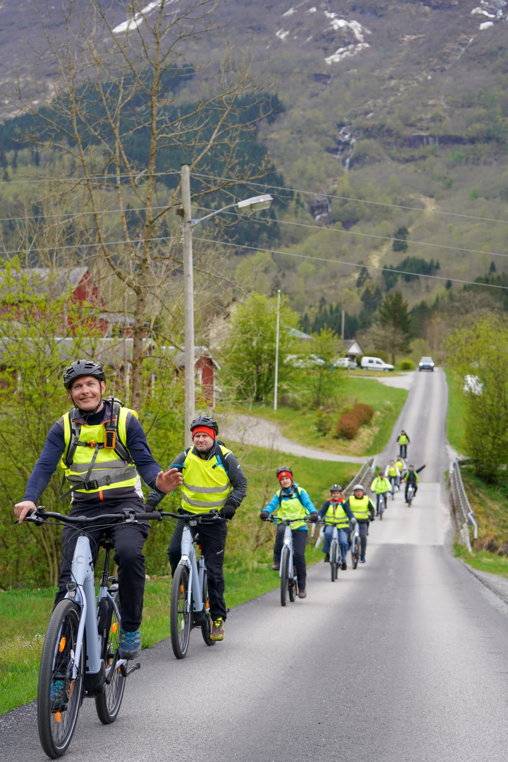 Guided group cycling on scenic rural road near fjord valley