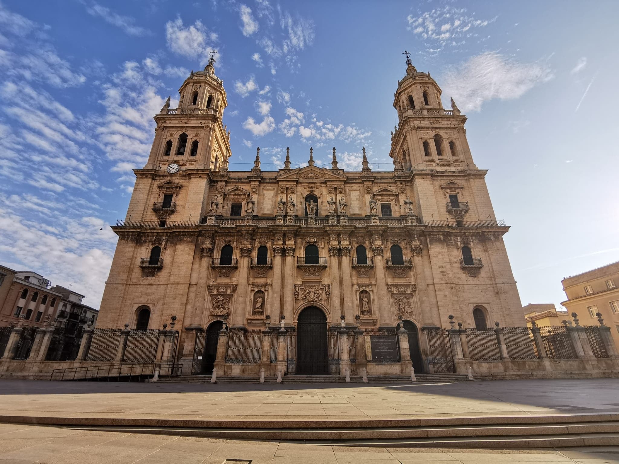 Grand cathedral facade in sunlit plaza, historic Spain tour