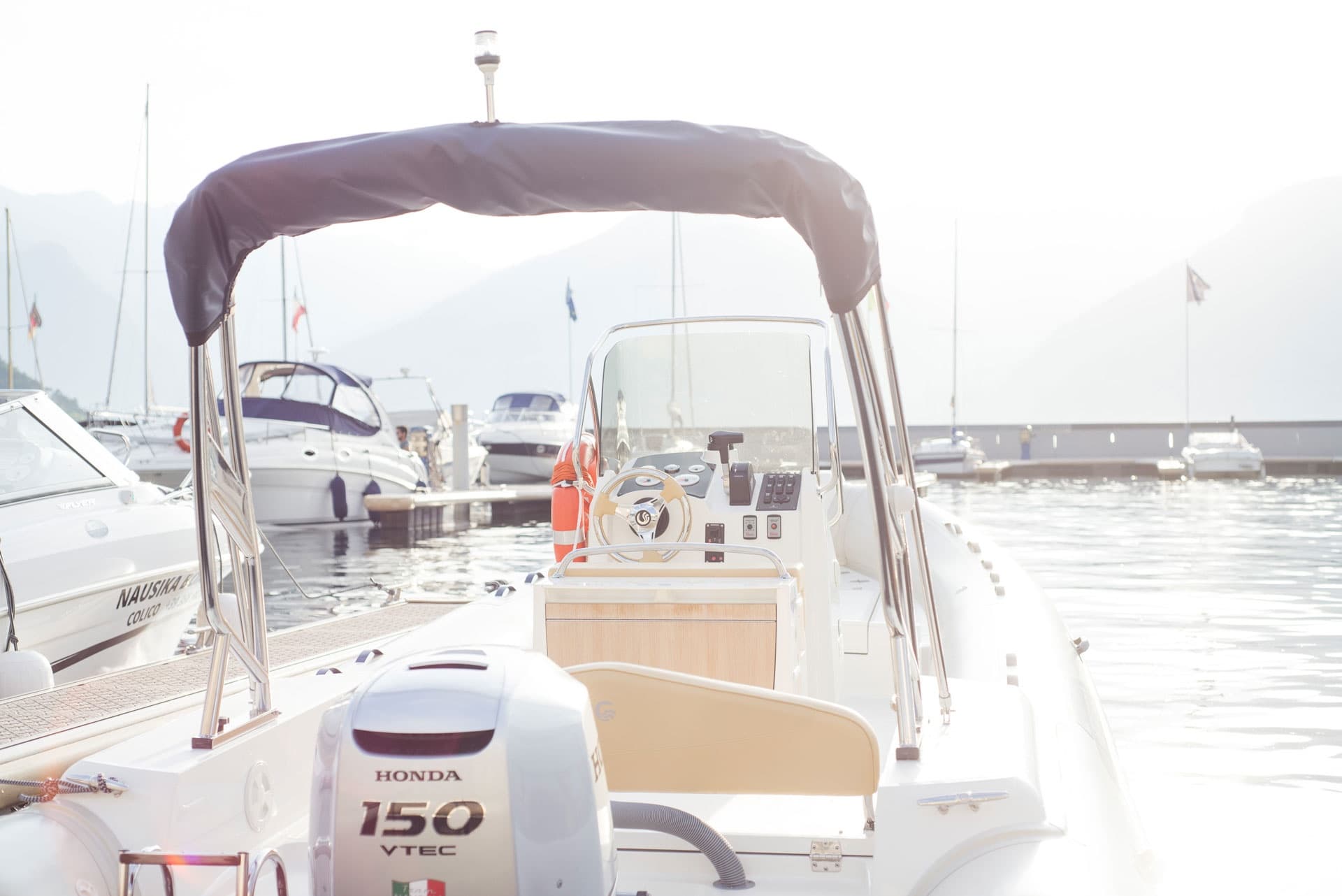 Bow and outboard of leisure boat docked in bright marina at sunrise