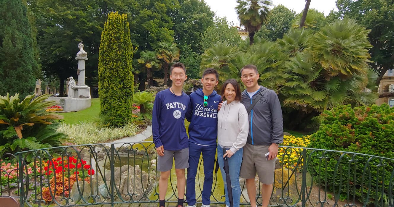 Friends posing in lush public garden near historic park in San Sebastián