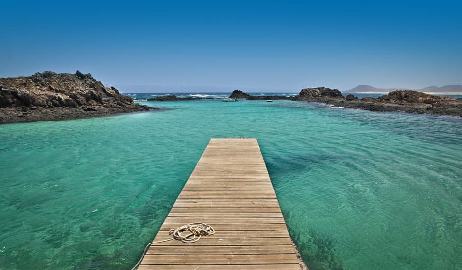Aerial turquoise bay with wooden pier and calm Mediterranean waters