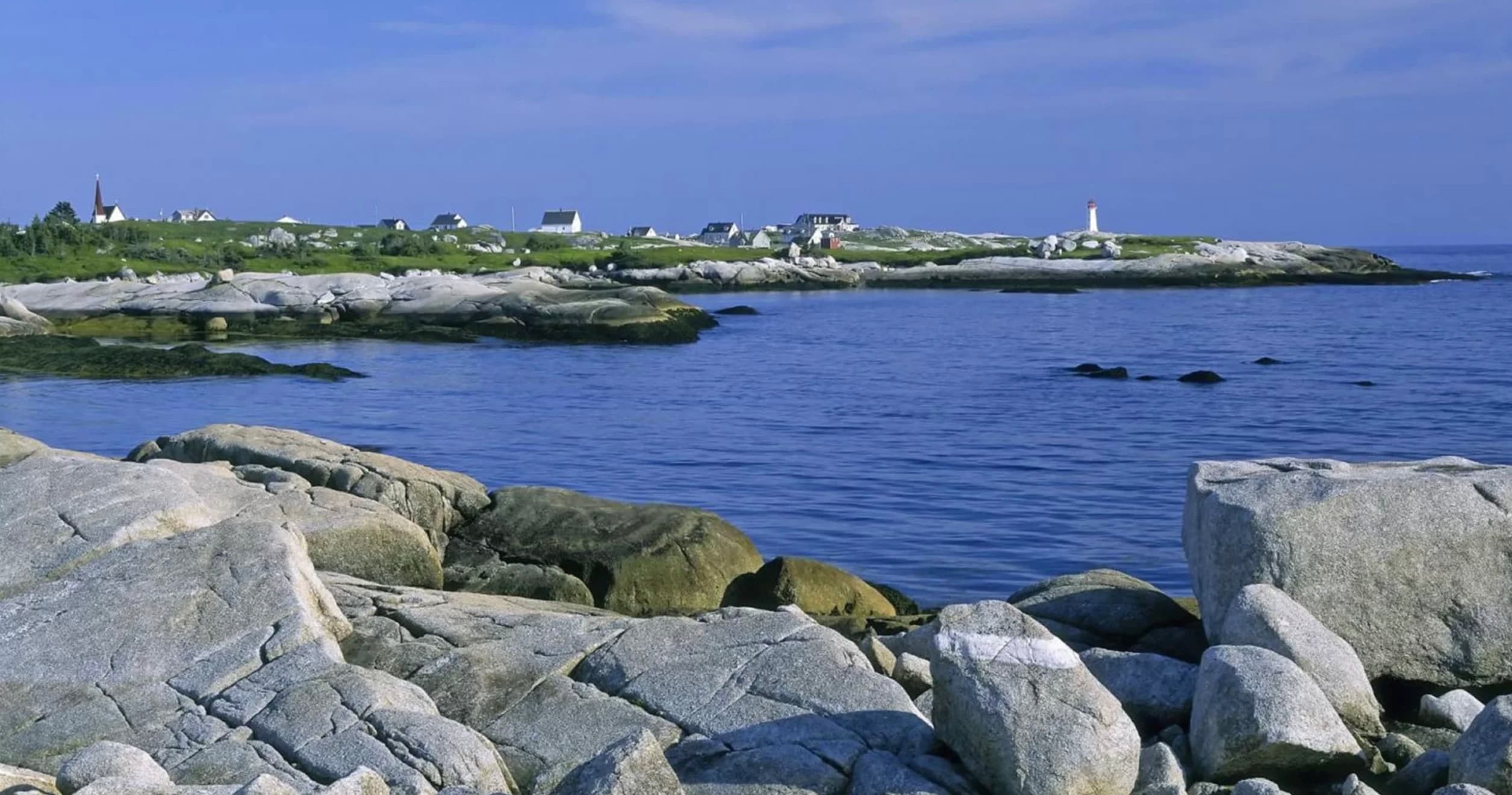 Boat approaching Peggy's Cove lighthouse across open ocean