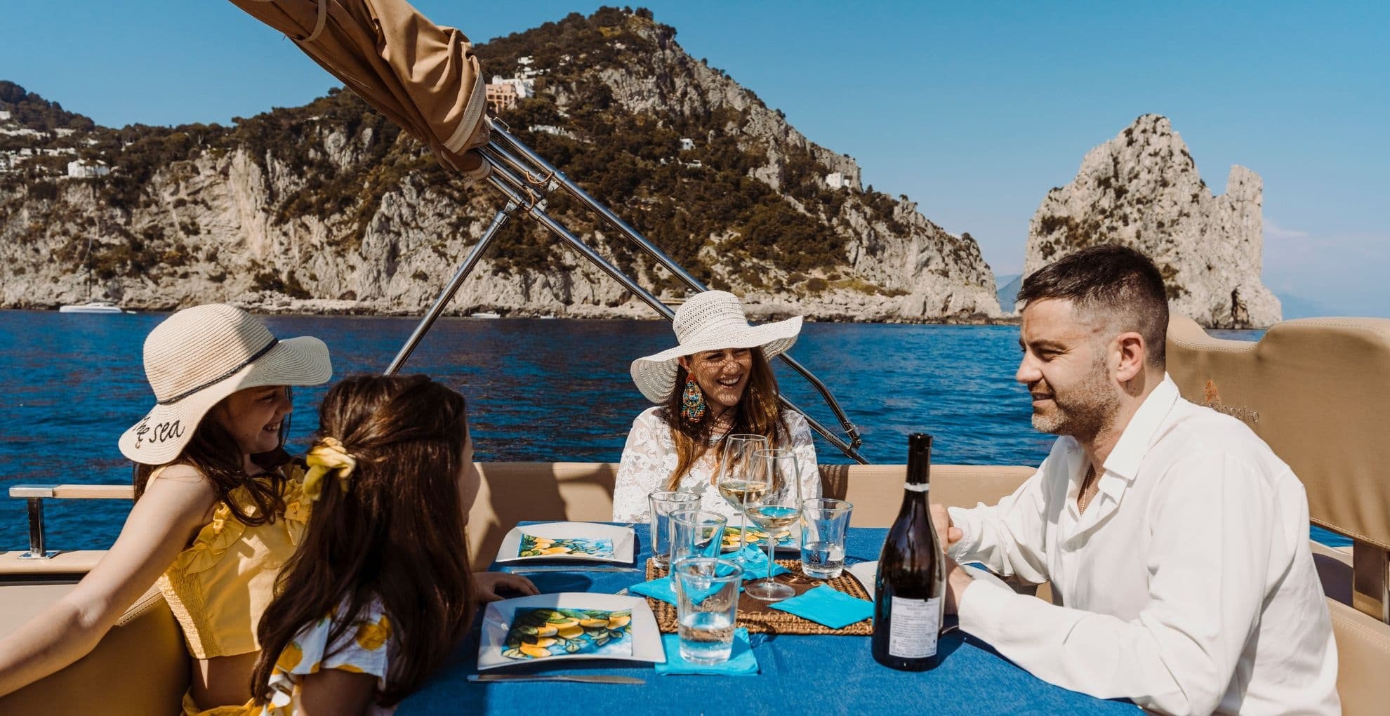 Friends dining on yacht deck with sea view and rocky island backdrop