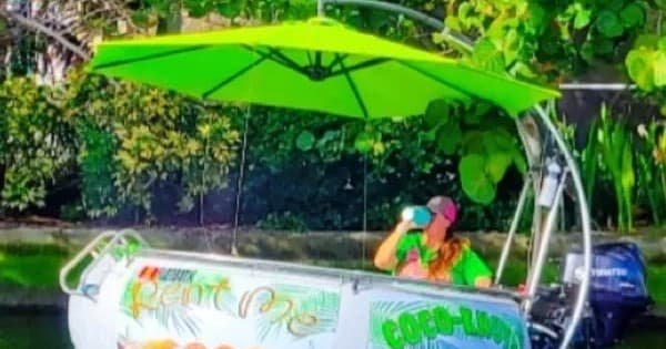 Floating novelty boat with green umbrella on tropical canal