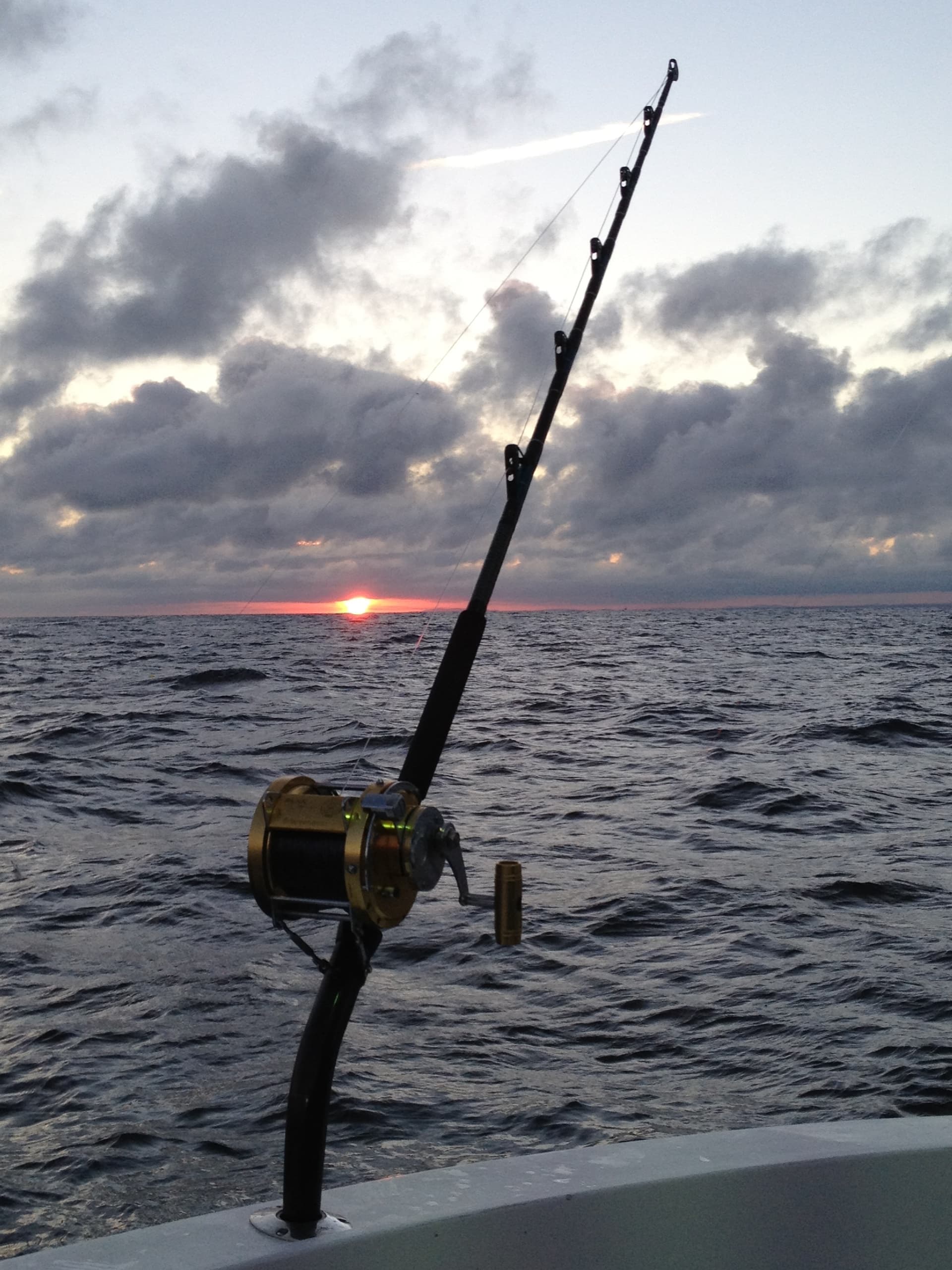 Deep sea fishing rod set against sunset over open ocean