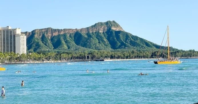 Beachgoers at Waikiki with Diamond Head volcanic crater in Honolulu