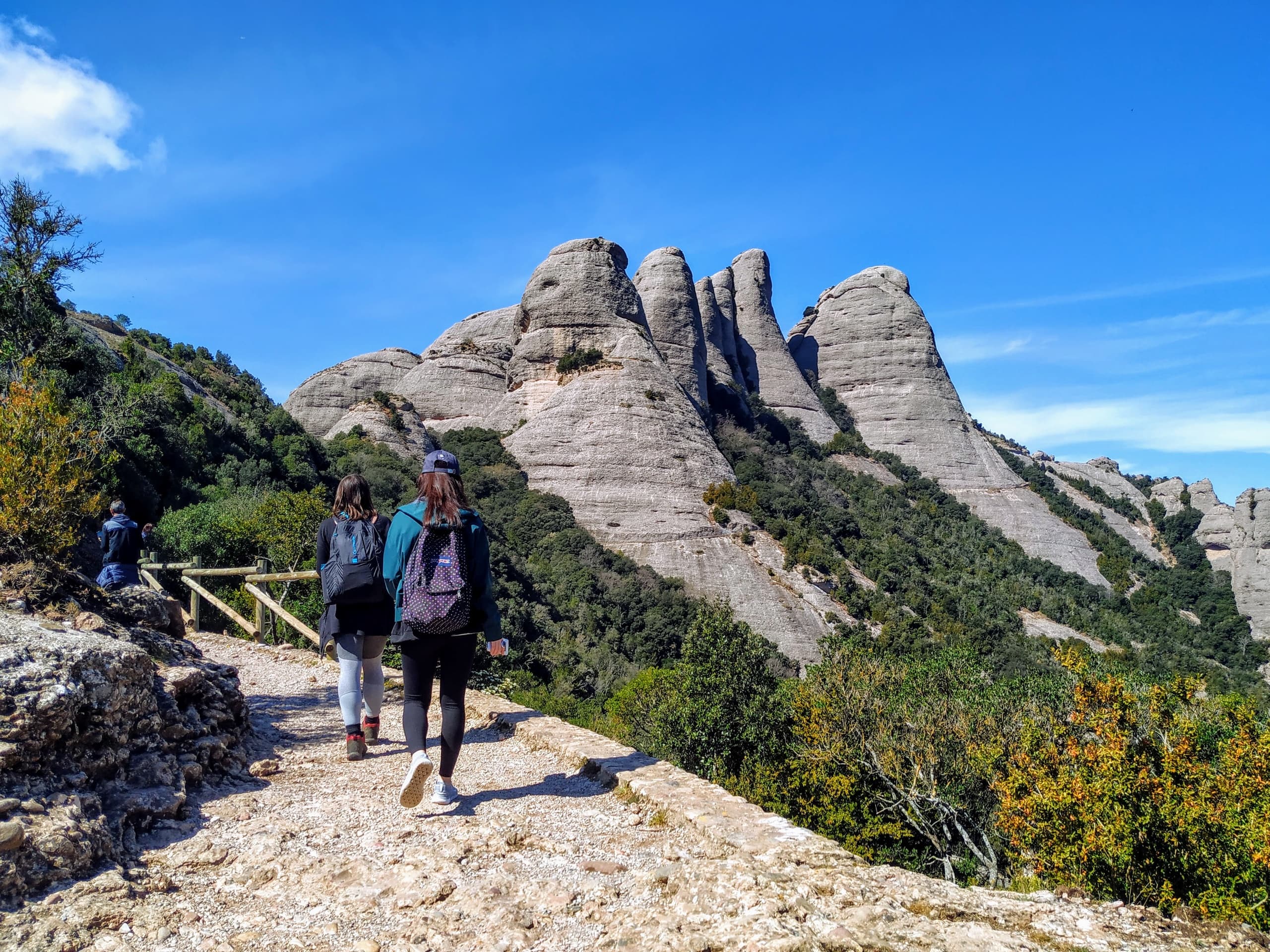 Hikers trekking rocky Montserrat trail with jagged peaks ahead