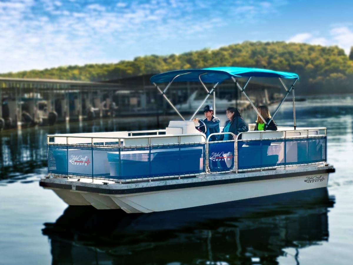 Pontoon boat docked on glassy coastal bay under trees