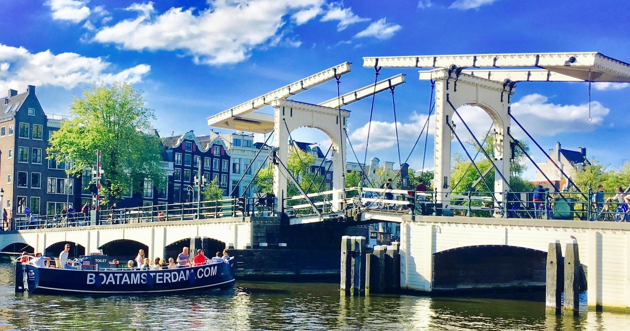 Historic canal with drawbridge and sightseeing boat in Amsterdam