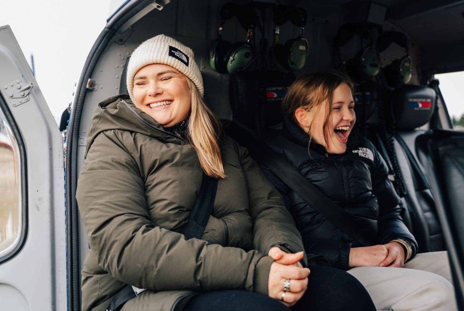 Two passengers smiling inside helicopter cabin during scenic tour