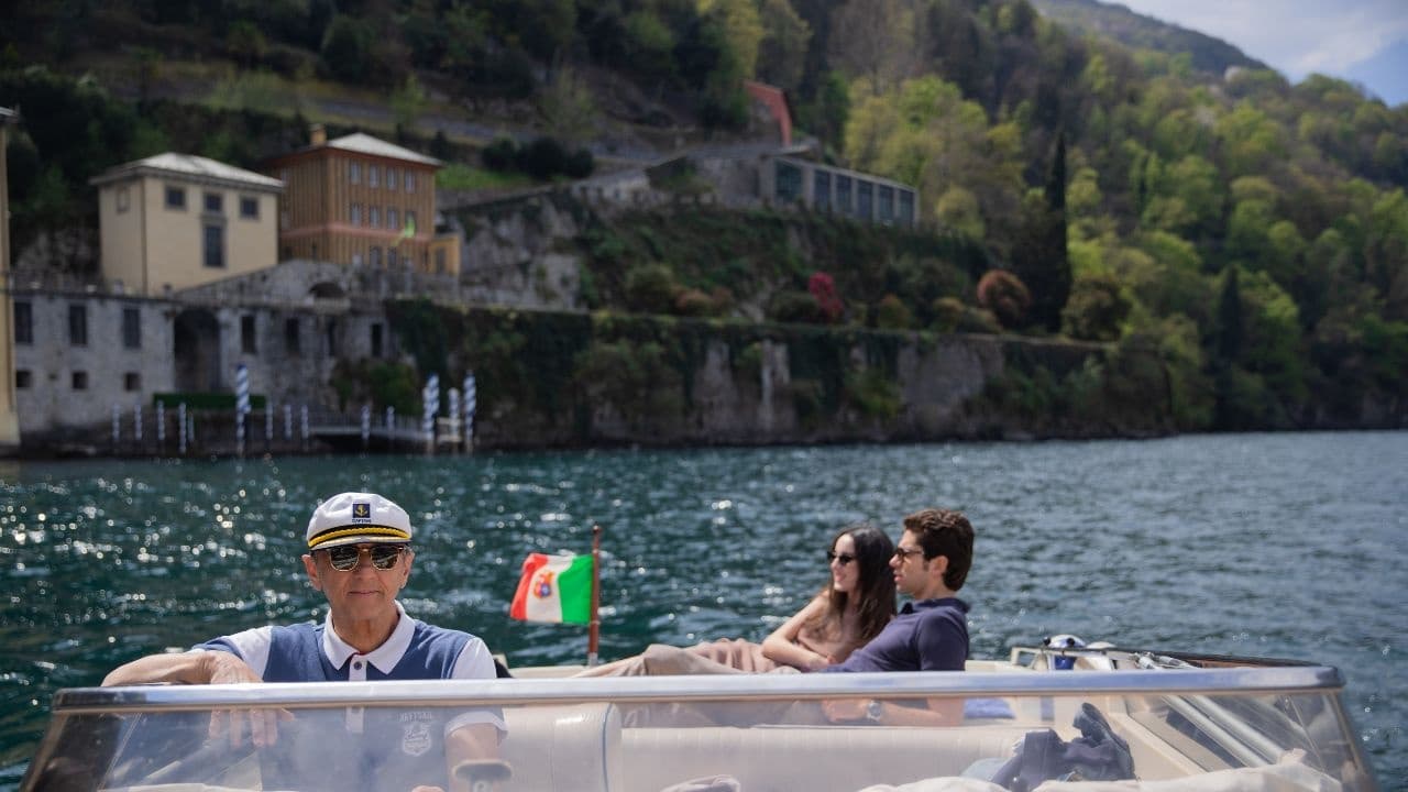 Couple and captain cruising on lake by hillside villas, boat tour