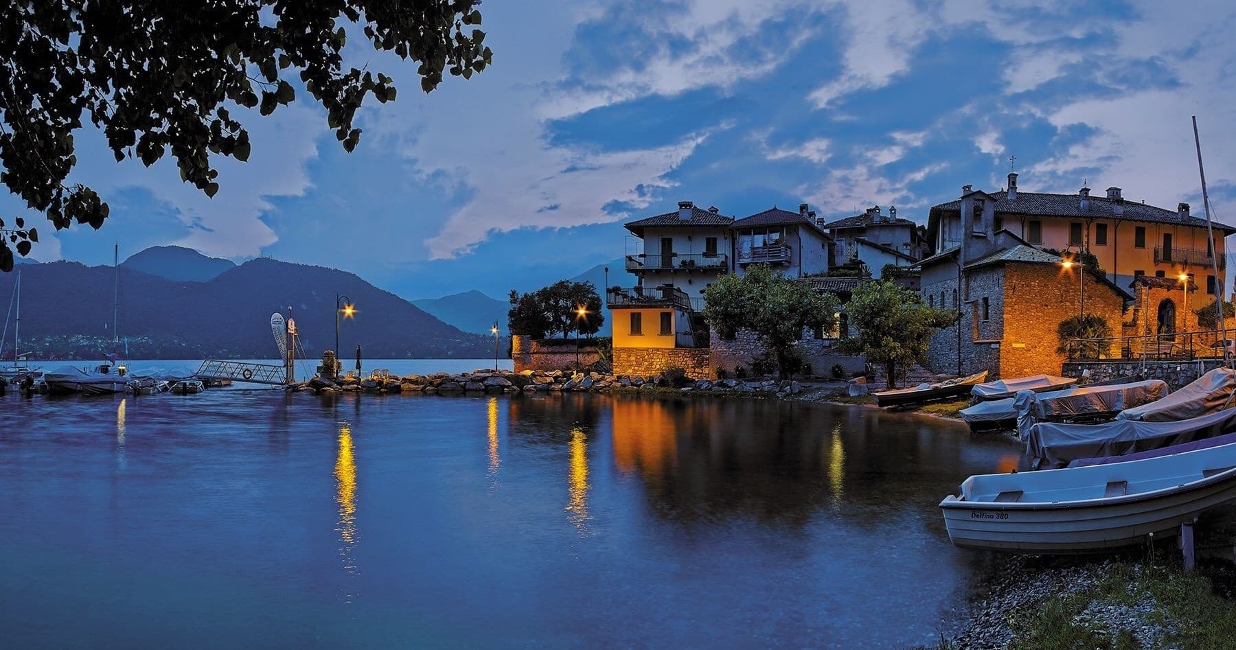 Dusk harbor village with moored boats reflecting lights