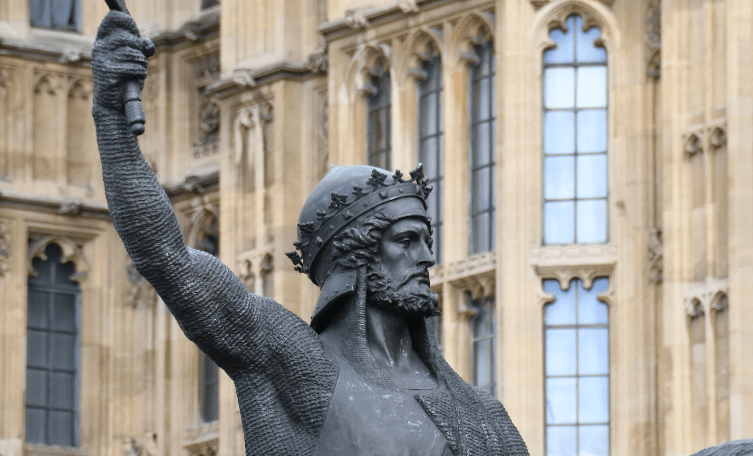 Bronze medieval king statue outside Gothic building, urban landmark