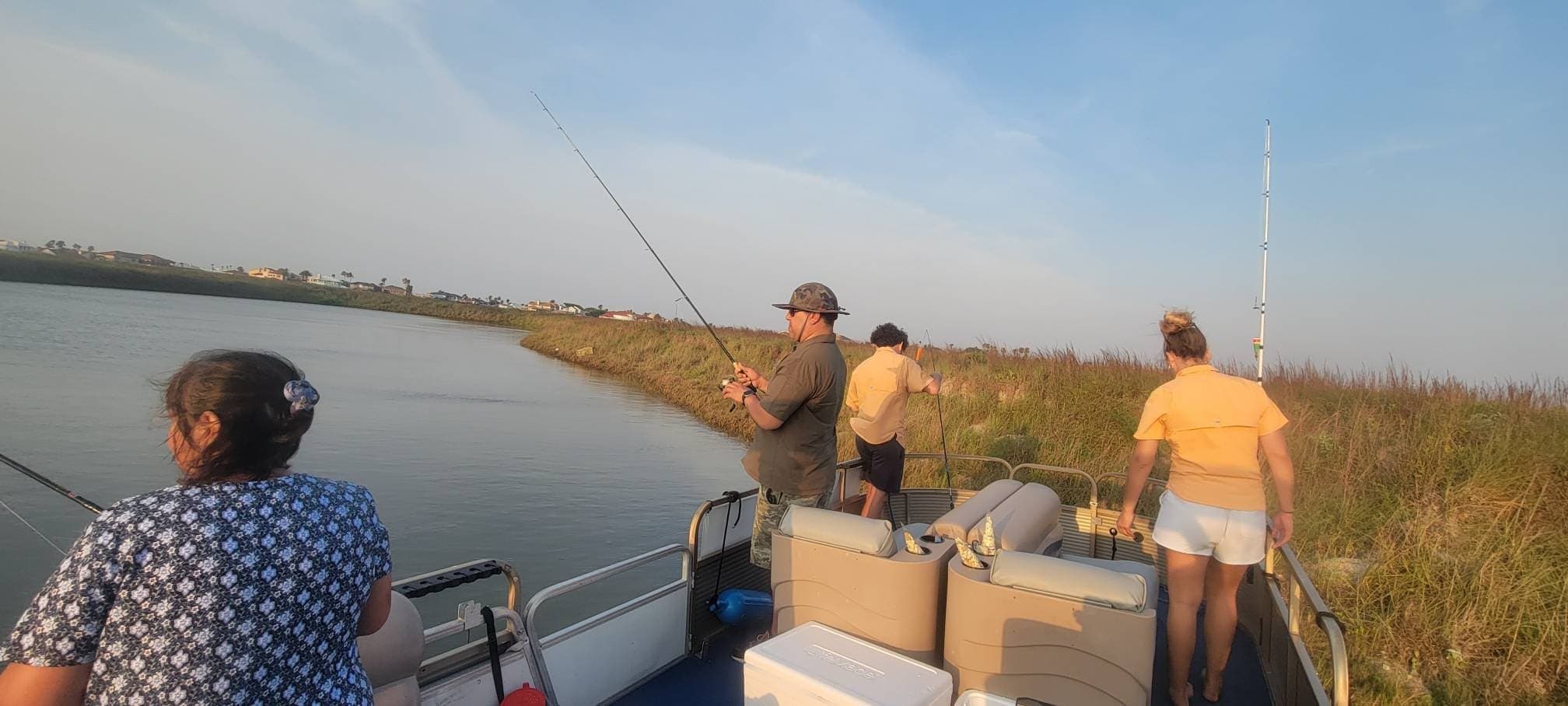 Anglers fishing from pontoon boat in coastal marsh at sunset