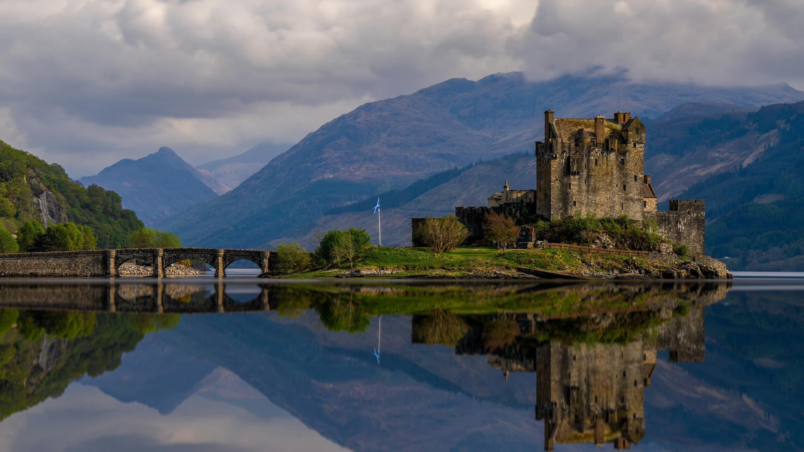 Castle reflected on calm loch with mountain backdrop at dusk