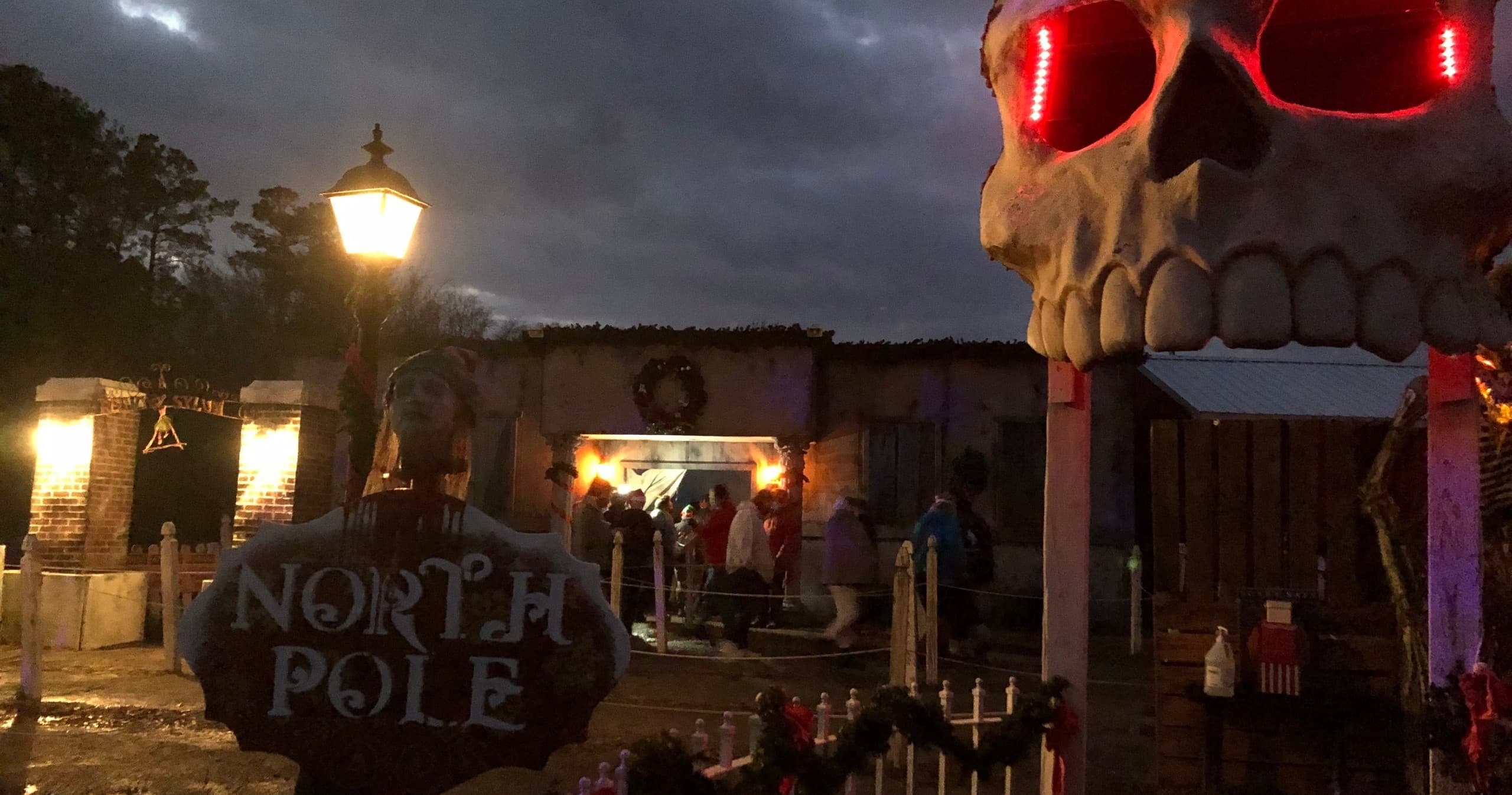 Haunted attraction exterior with giant skull entrance, night