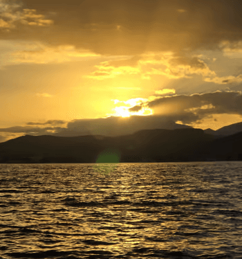 Boat cruising at sunset off Mallorca coast, golden sea view