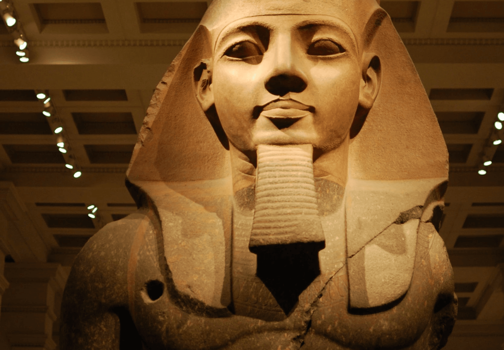 Large Egyptian pharaoh statue in museum gallery, historical exhibit