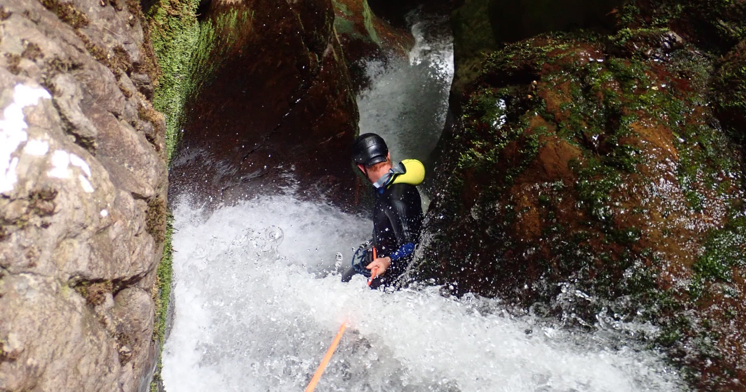 Canyoning participant abseiling down waterfall in Scottish gorge