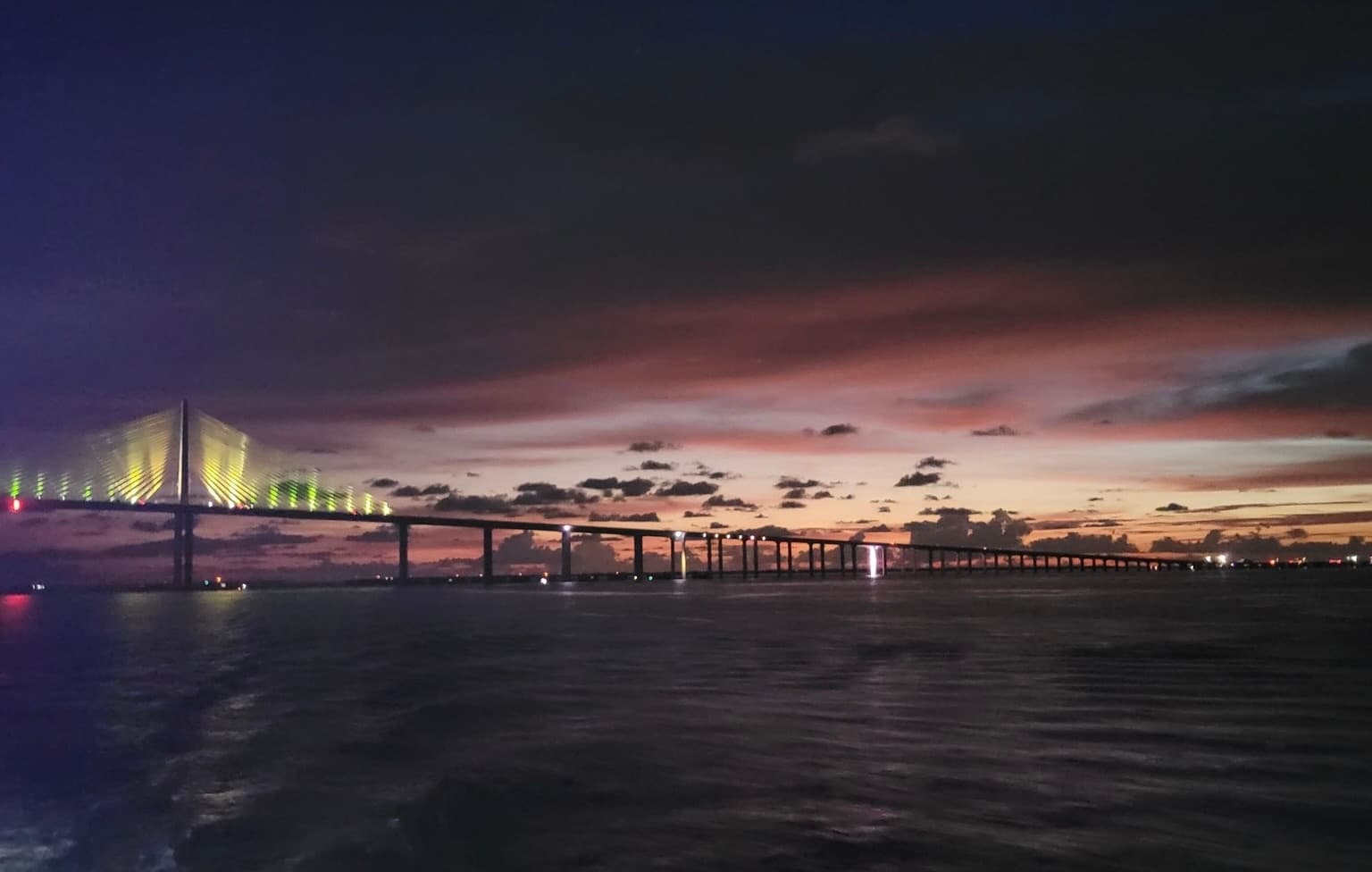 Sunset bridge skyline over bay with evening boat cruise