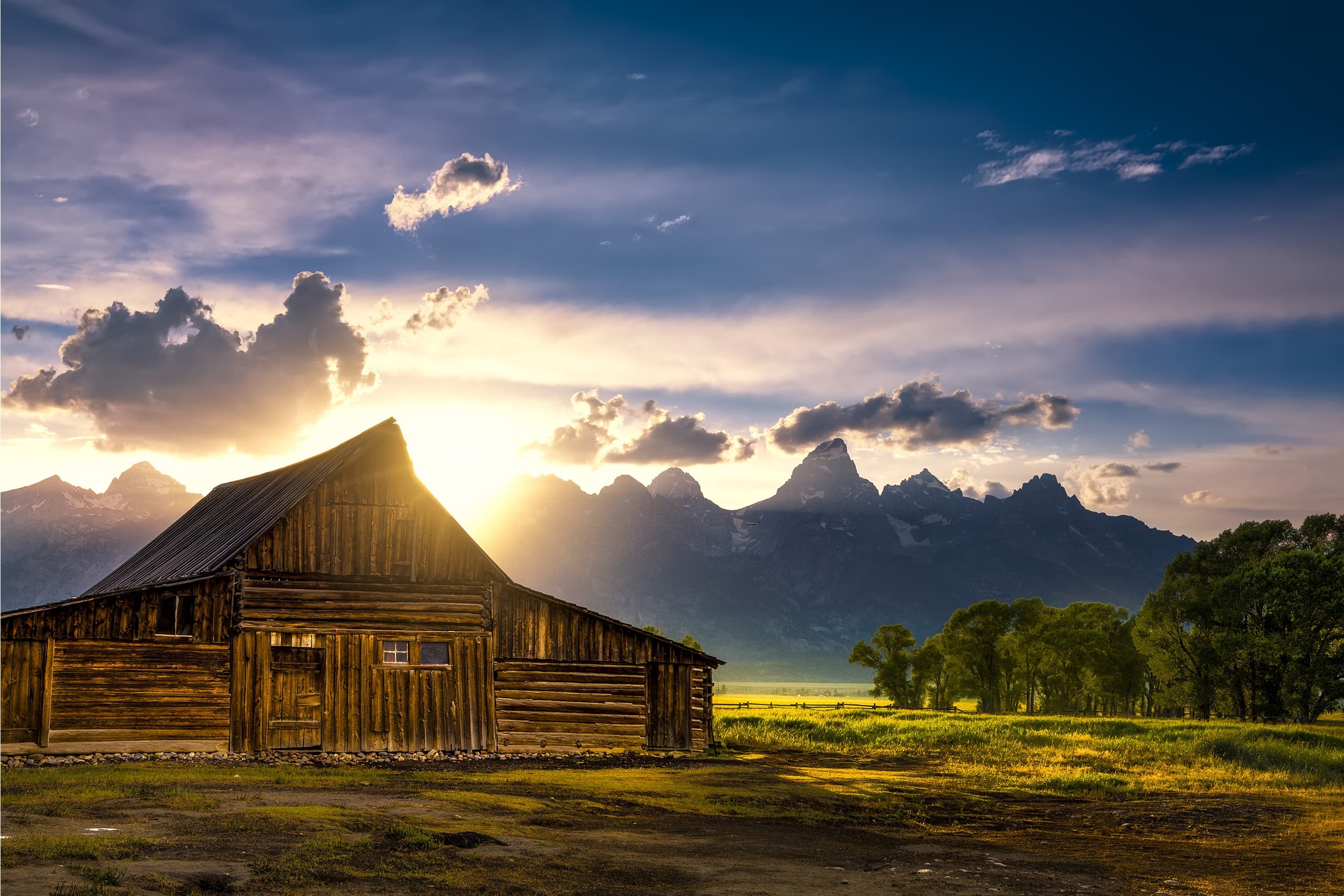 Rustic barn at sunrise with mountain range and dramatic sky