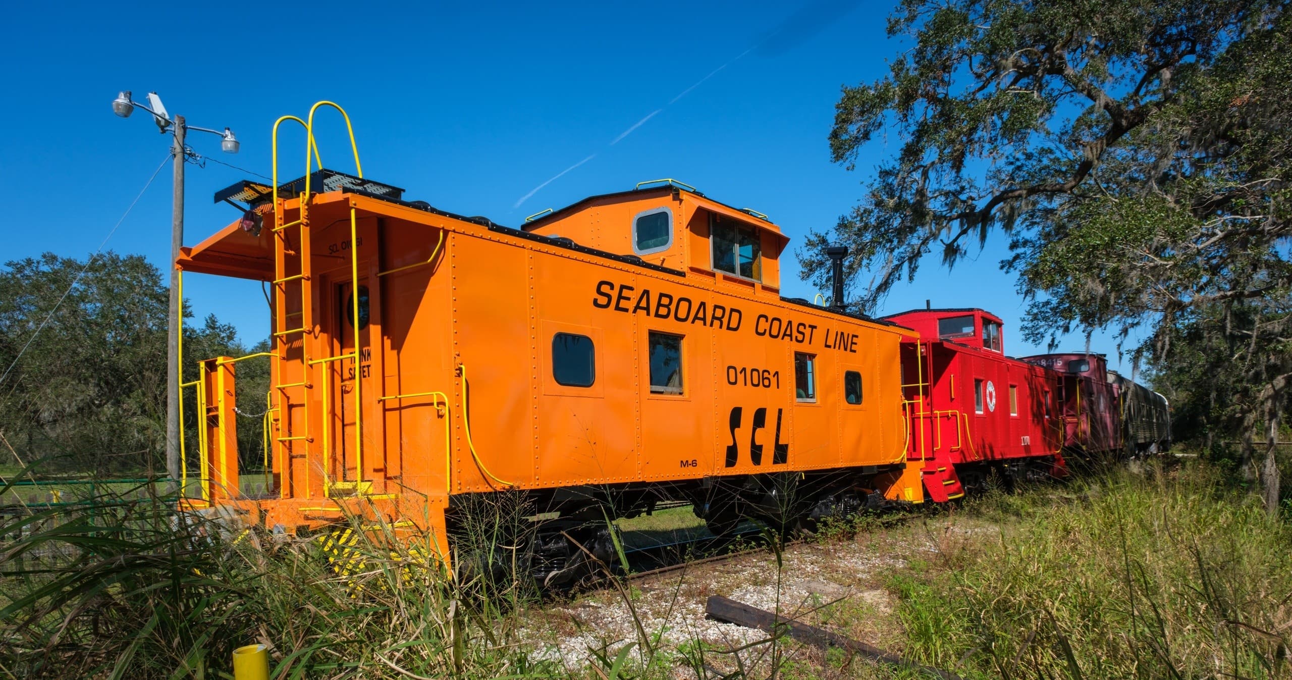 Bright orange caboose photographed on sunny vintage railroad sidings