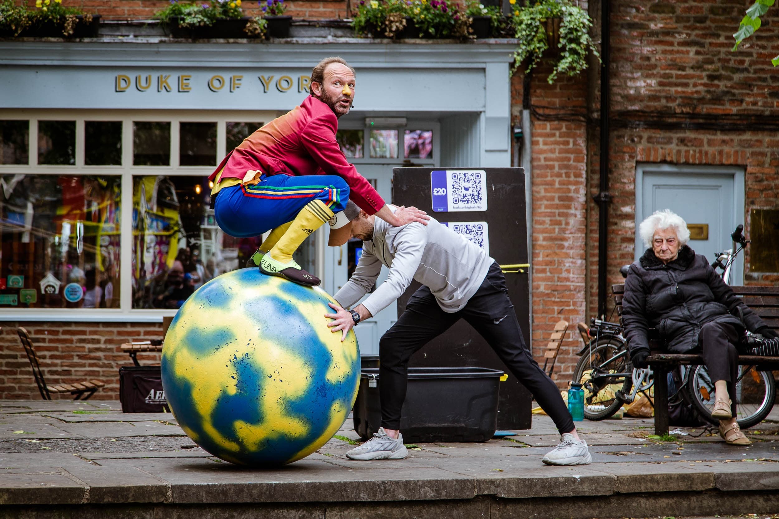 Street performers balancing on giant globe in York city center