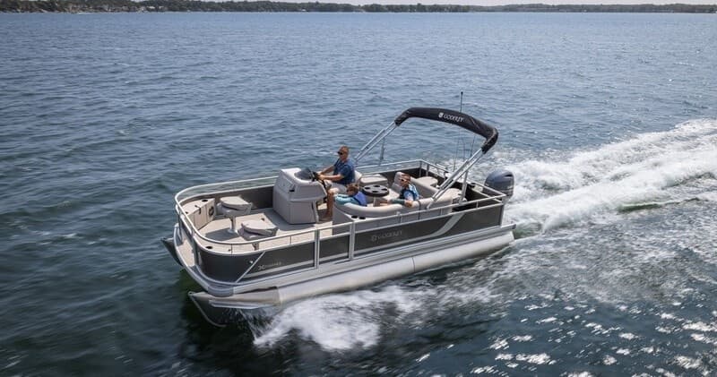 Pontoon boat gliding on calm lake near resort docks