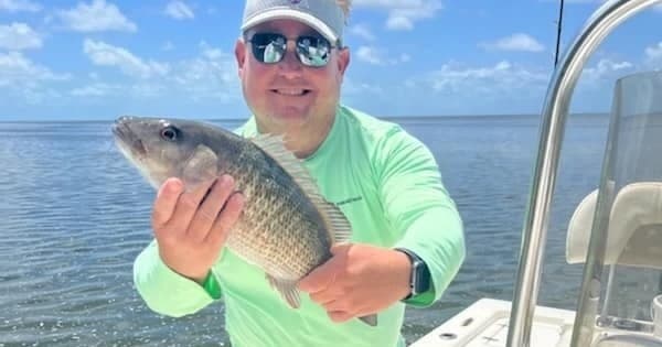 Angler holding redfish on charter boat in tropical flats