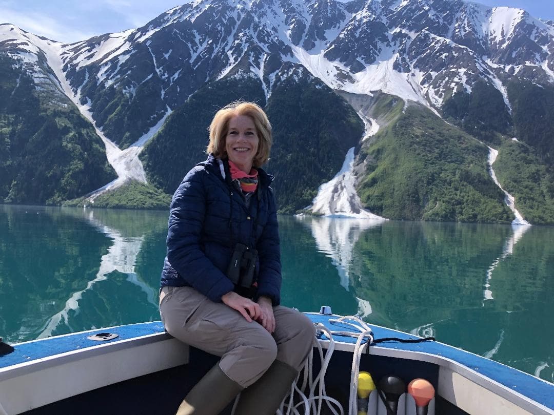 Woman boating in alpine fjord with snowcapped mountains, Alaska