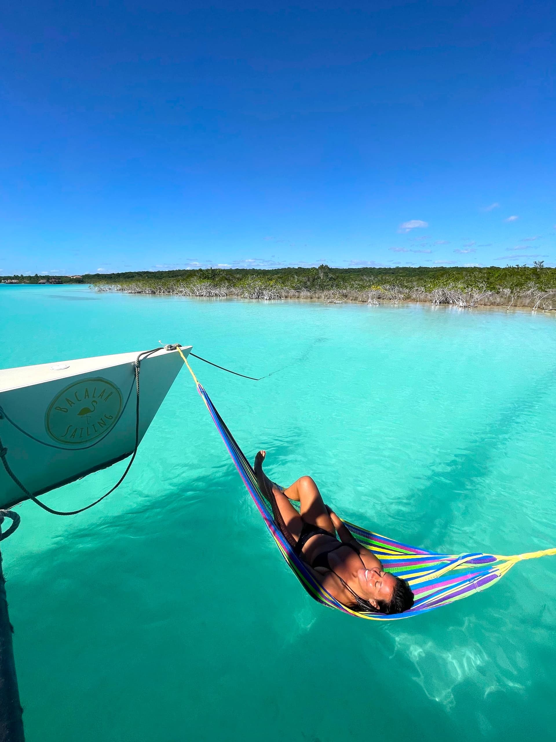 Traveler lounging in hammock over crystal turquoise ocean water