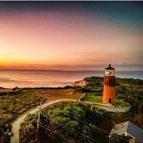 Aerial lighthouse at sunset over rugged coast, scenic viewpoint