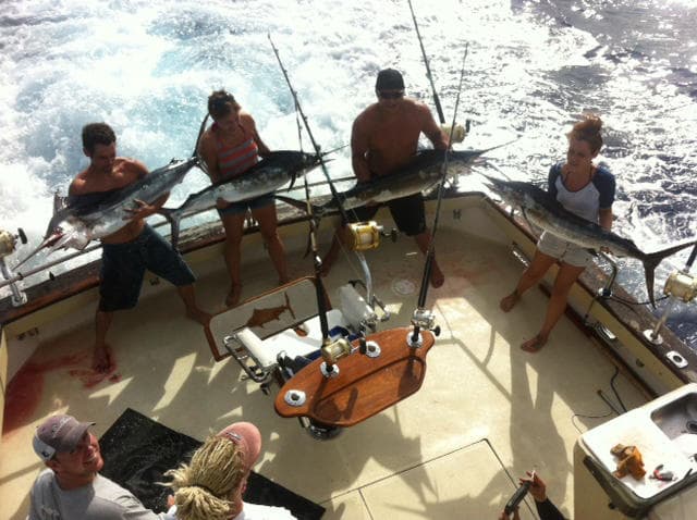 Anglers displaying mahi-mahi on boat deck during deepsea trip