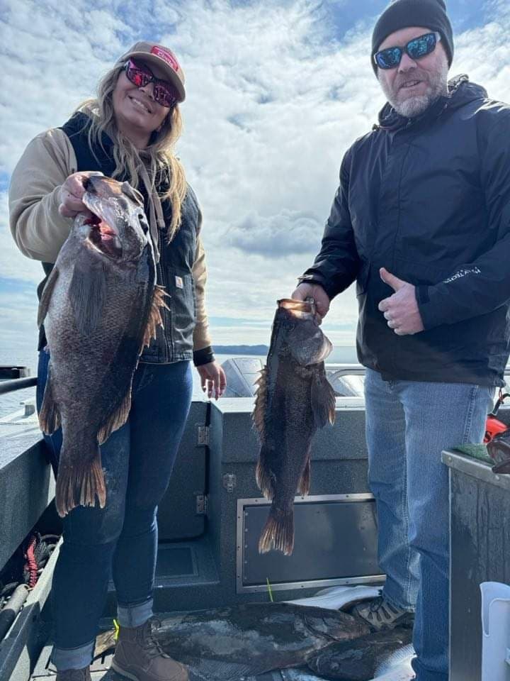 Anglers holding black cod on boat deck during Alaskan fishing trip