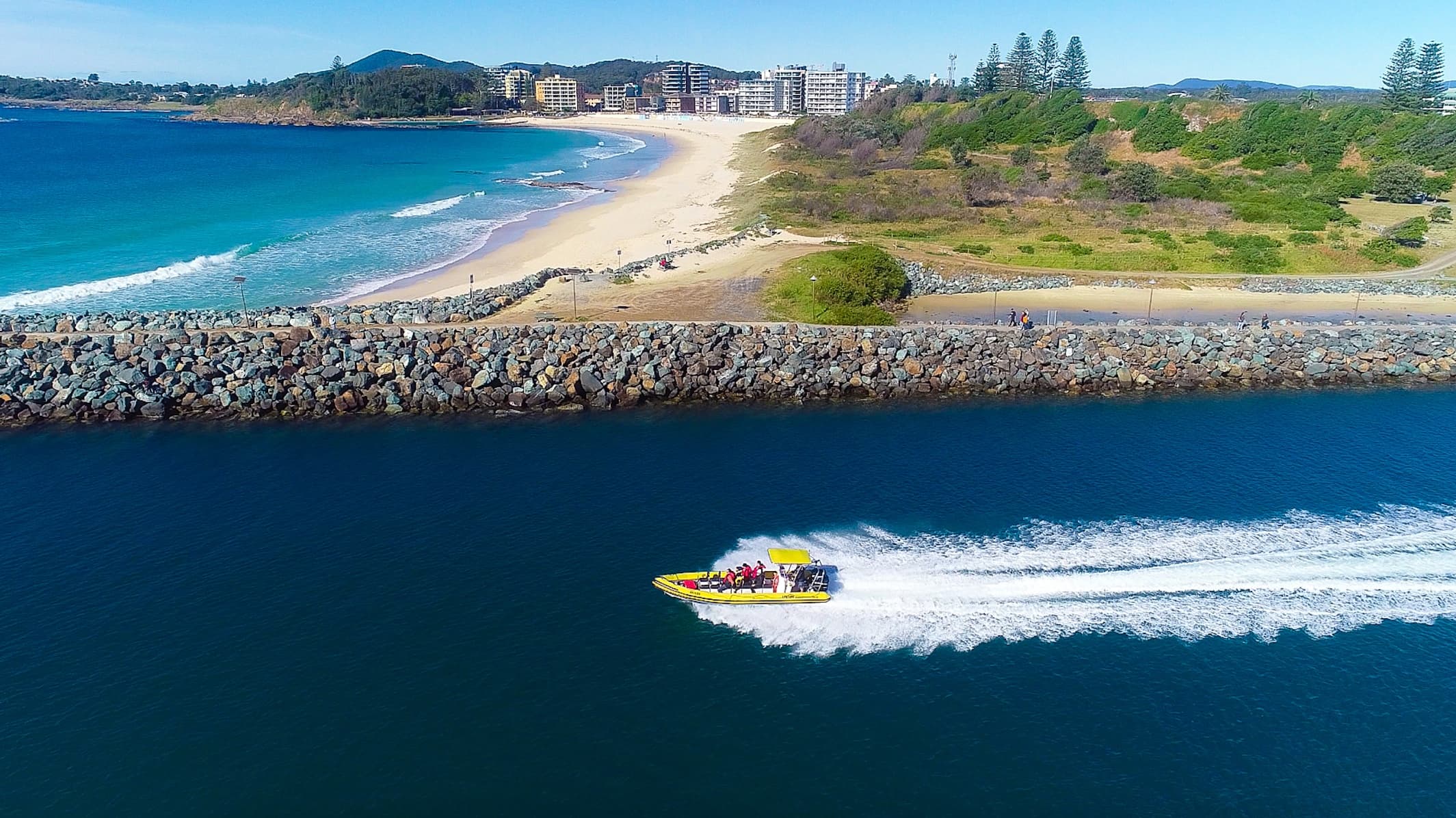 High-speed powerboat skimming ocean near sandy coastal headland