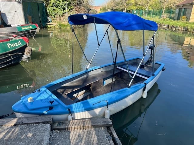 Blue electric tour boat docked on tranquil canal with reflections