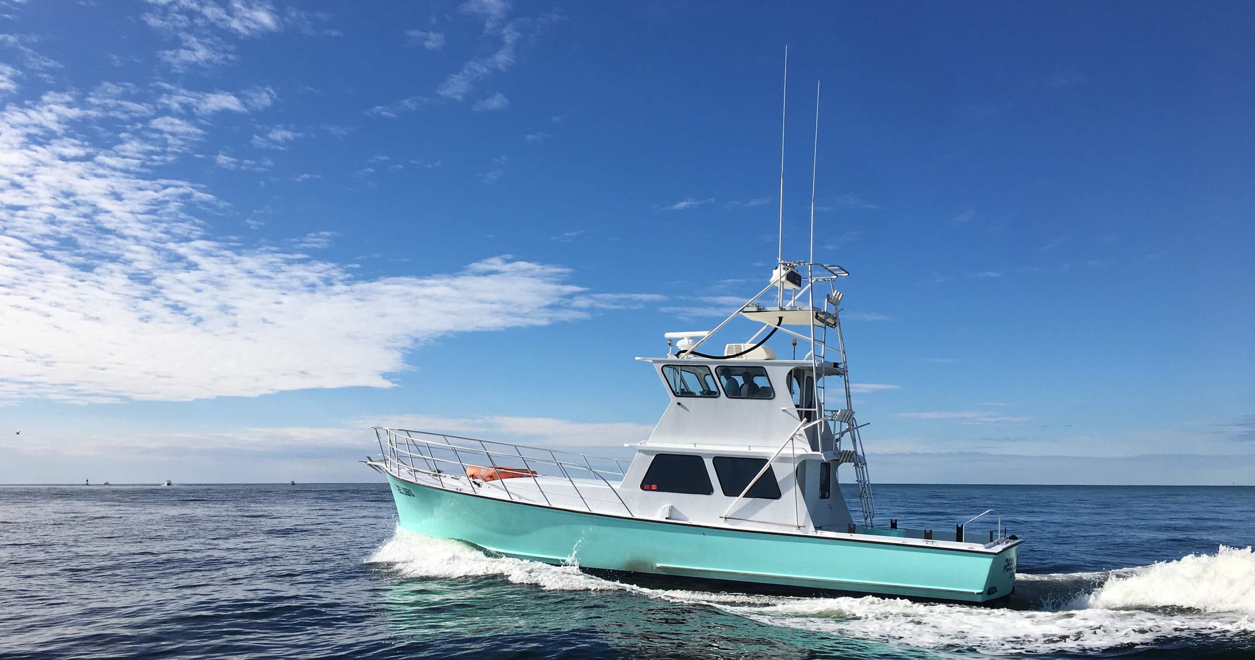Sportfishing charter boat cruising offshore with blue sky vistas