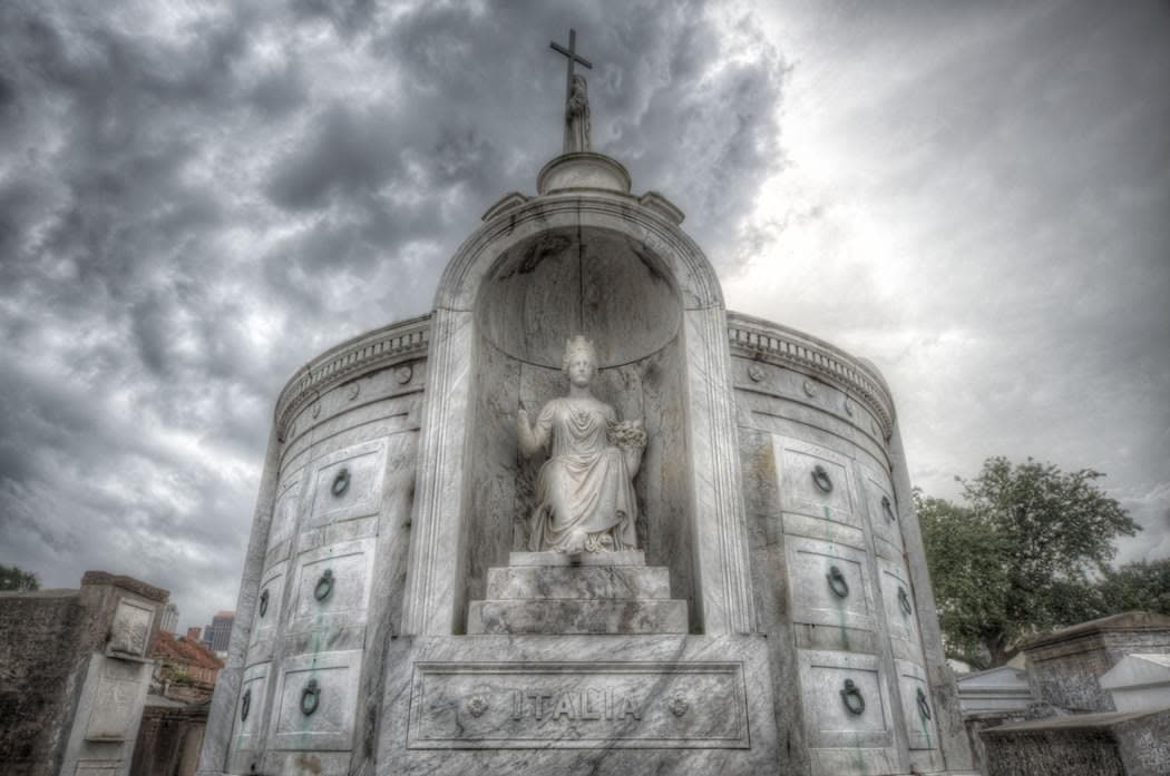 Stone mausoleum with dramatic clouds in outdoor cemetery