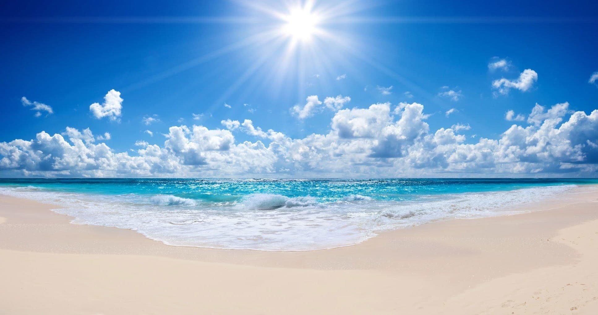 Scenic sunny beach shoreline with calm waves, ideal for surfing