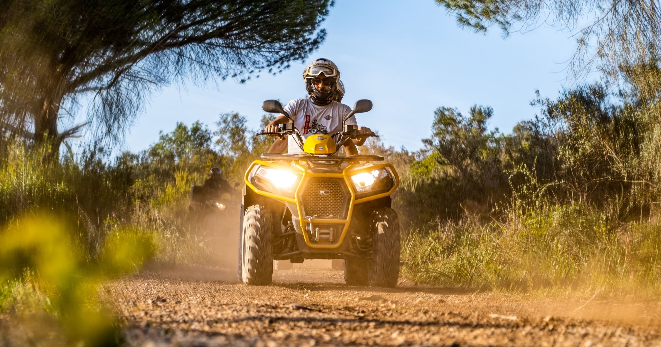 Rider on ATV kicking up dust on forested dirt track