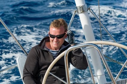 Skipper helming sailboat in open sea enjoying coastal sailing