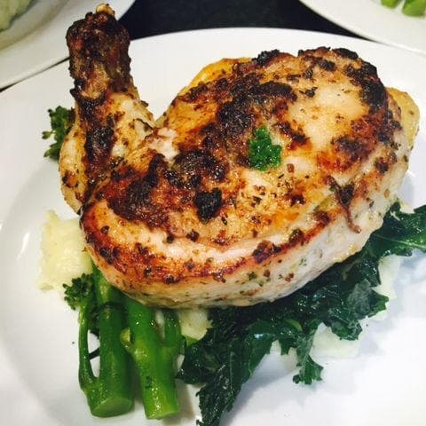 Grilled chicken chop served with greens on dining plate