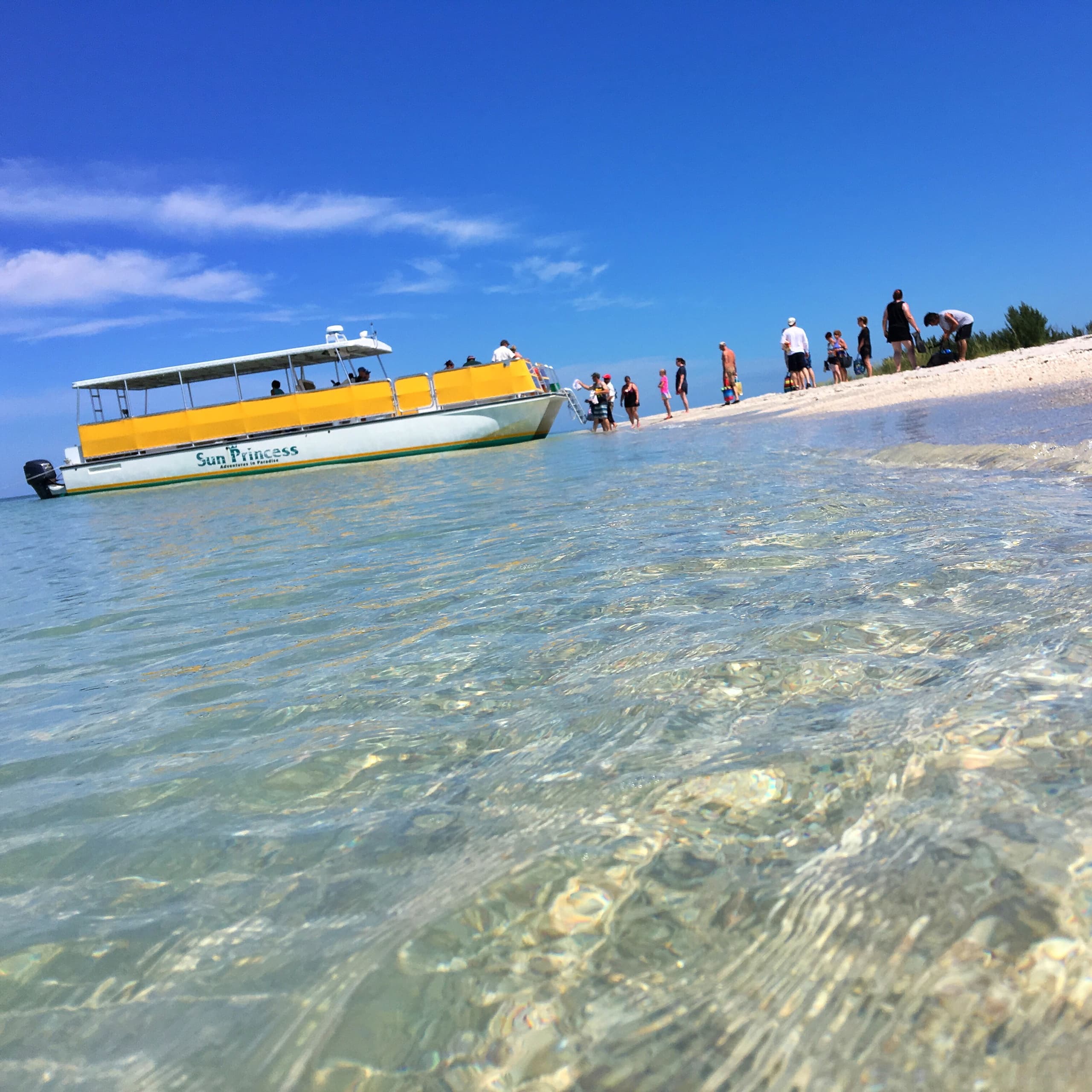Yellow tour boat anchored at clear sandbar near Fort Myers Beach