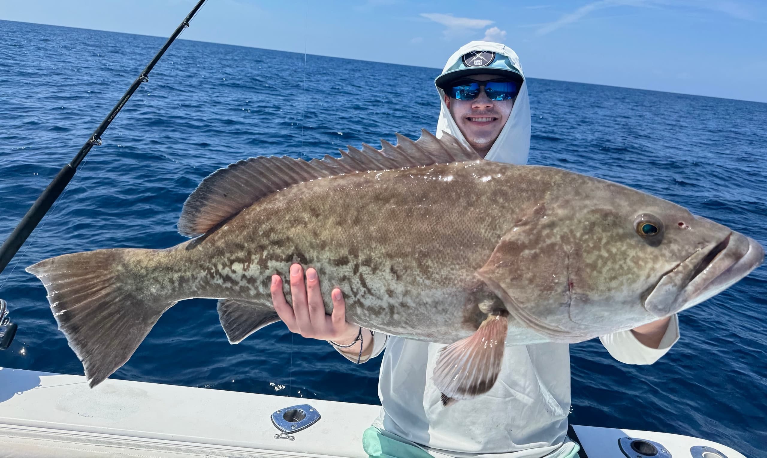 Angler holding large grouper on offshore blue-water fishing trip