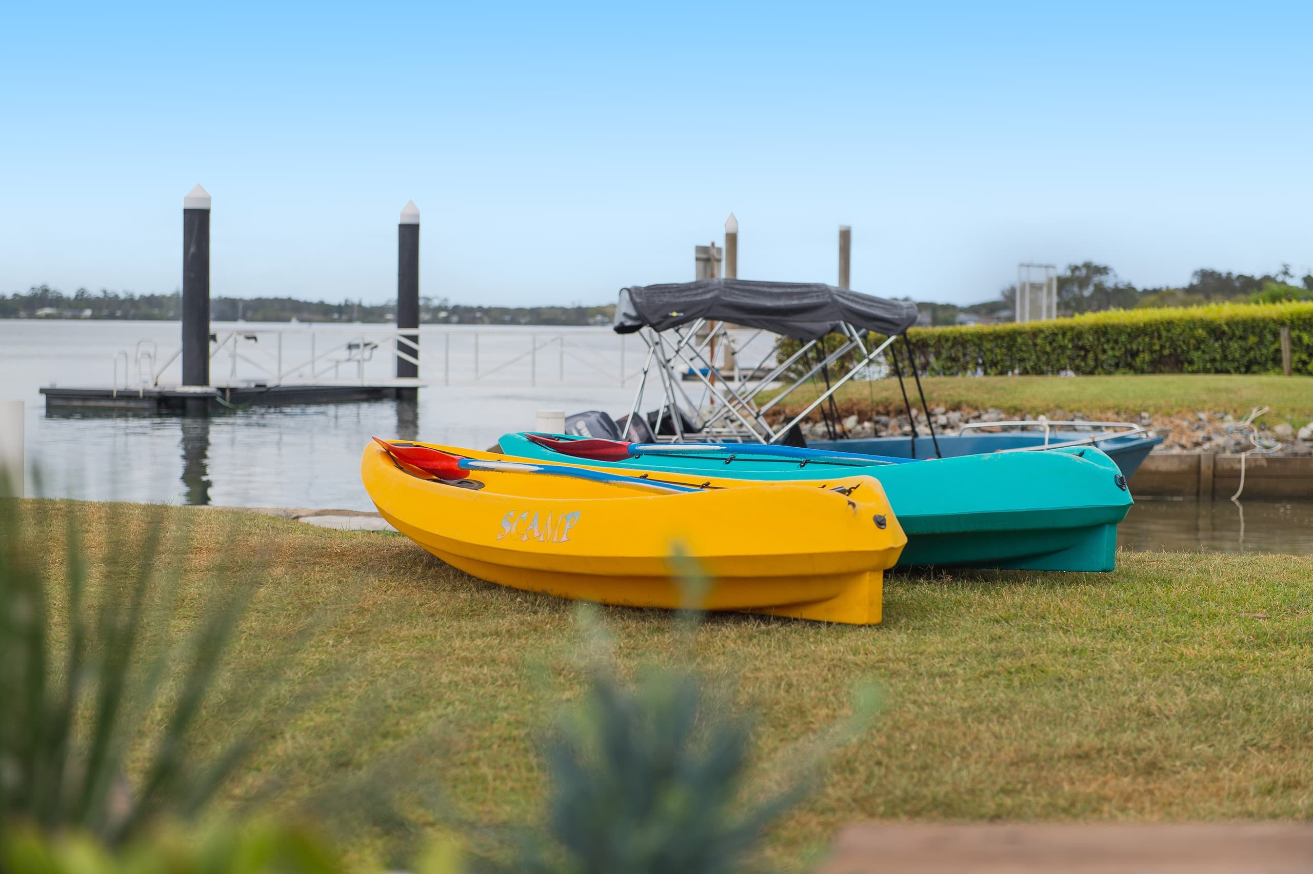 Colorful kayaks and small boats on shoreline grass near marina